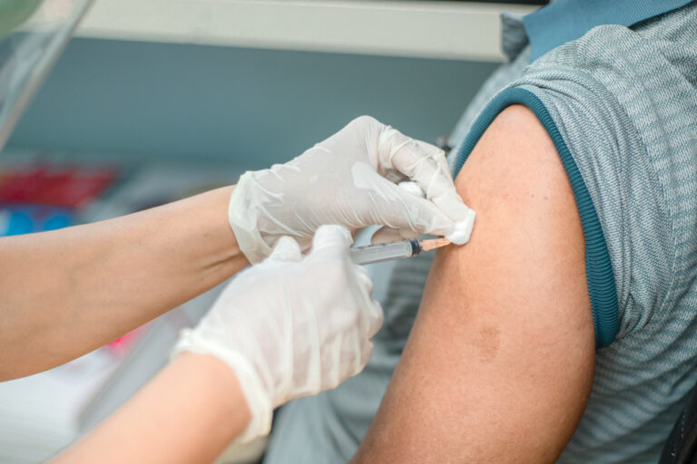 healthcare worker wearing gloves holding vaccine near patient's arm