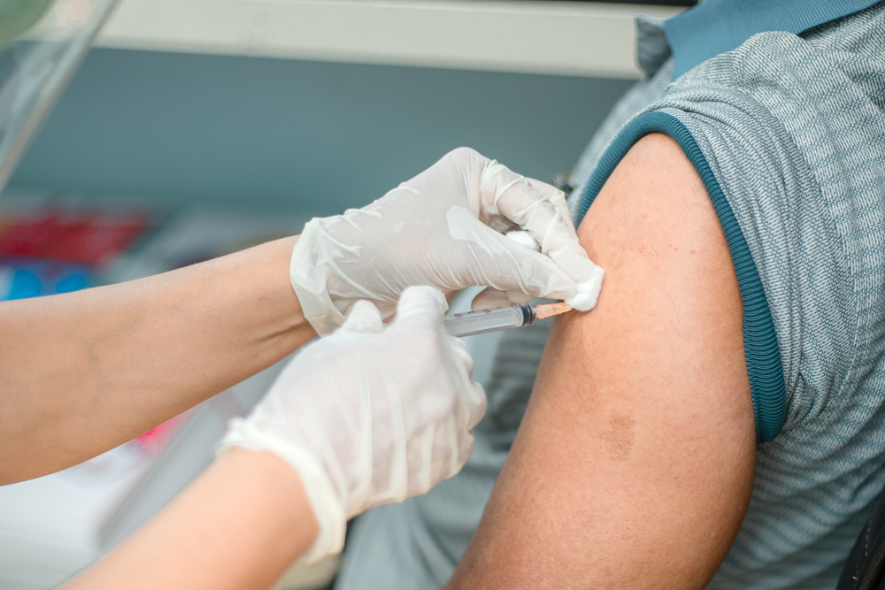 healthcare worker wearing gloves holding vaccine near patient's arm
