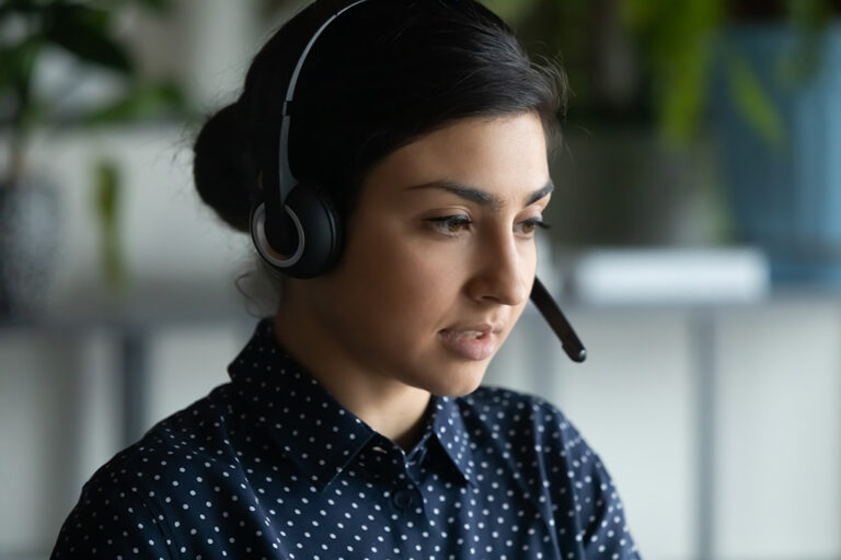A woman wearing modern wireless headset with microphone consulting on a video call