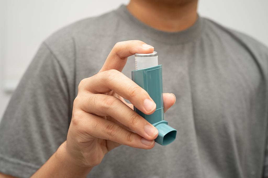 Male holding blue inhaler, suggestive of asthma and/or COPD