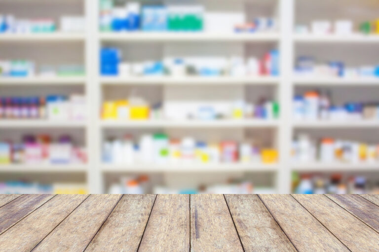 Wood counter with blur shelves of drugs in the pharmacy