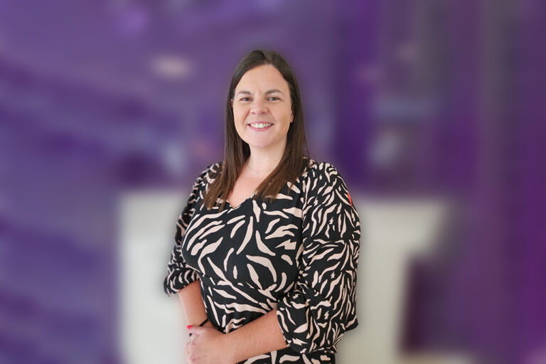 Elen Jones stands smiling in front of a purple background
