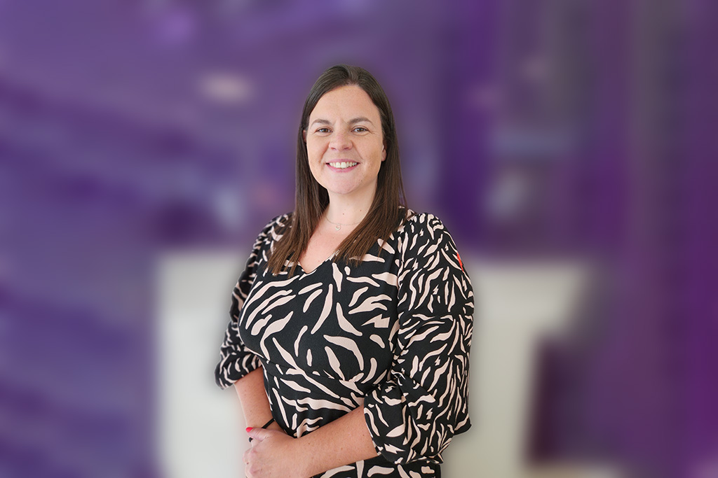 Elen Jones stands smiling in front of a purple background