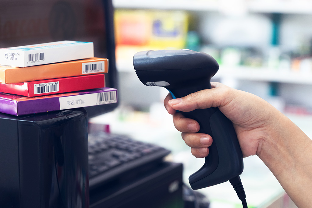 Pharmacist scanning price on medicine boxes with barcode reader in pharmacy store
