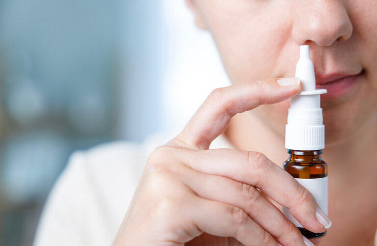 Close up shot of sick young woman using nasal spray