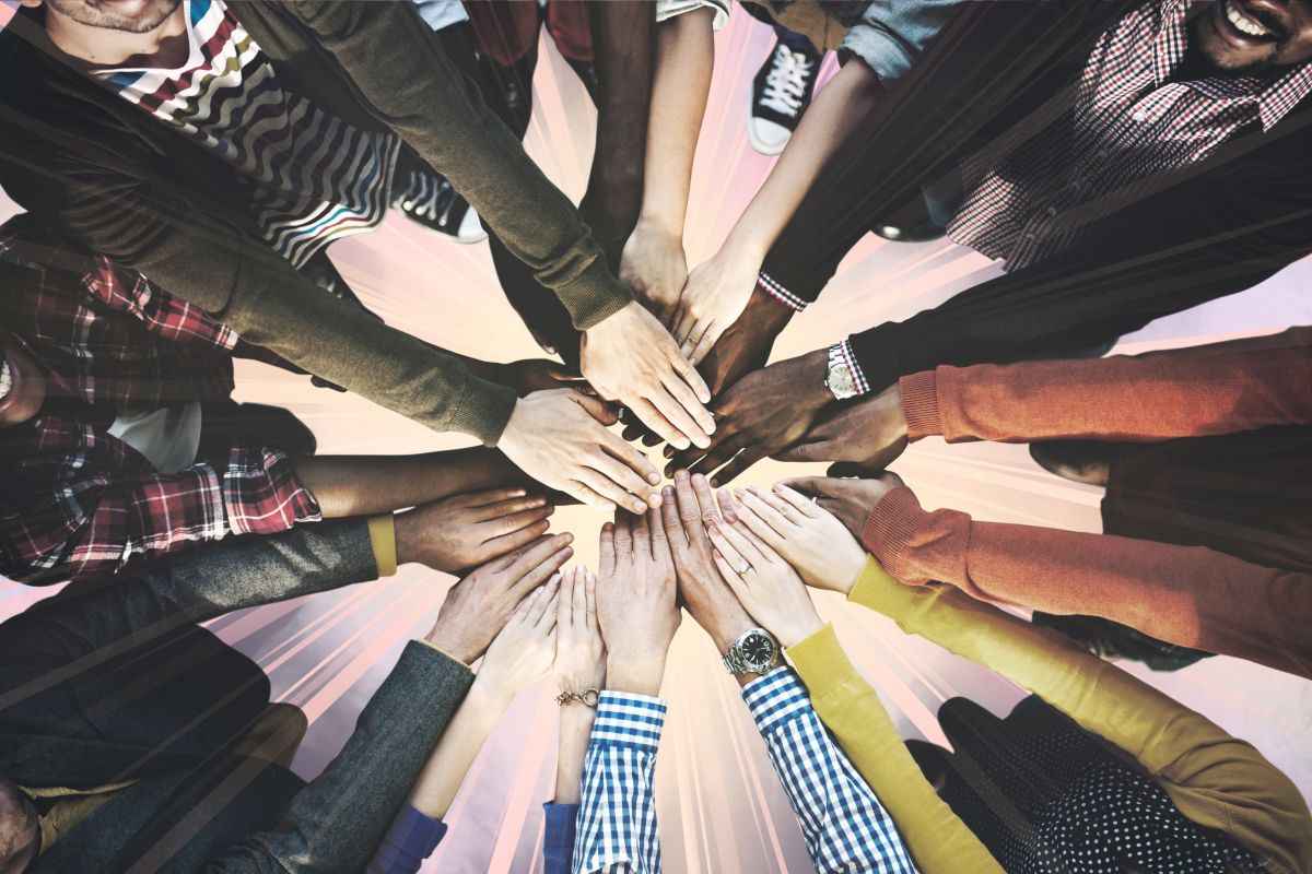 Top view of several arms and hands meeting in the middle, of varying ethnicities