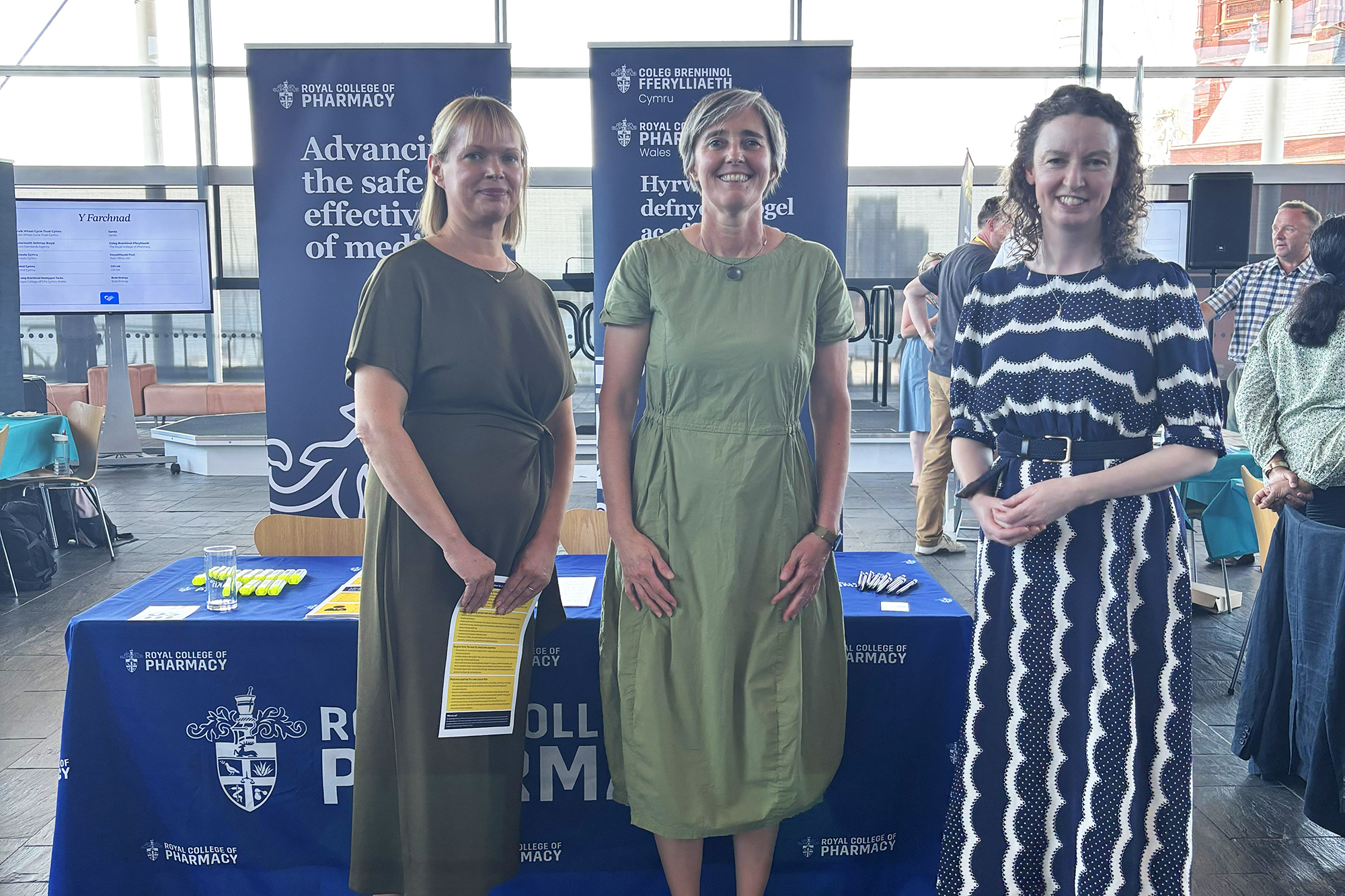 Liz Hallet (left) standing with Lyn Ackerman MS (middle) and Geraldine McCaffrey (right) in front of an RC Pharm booth with a window behind