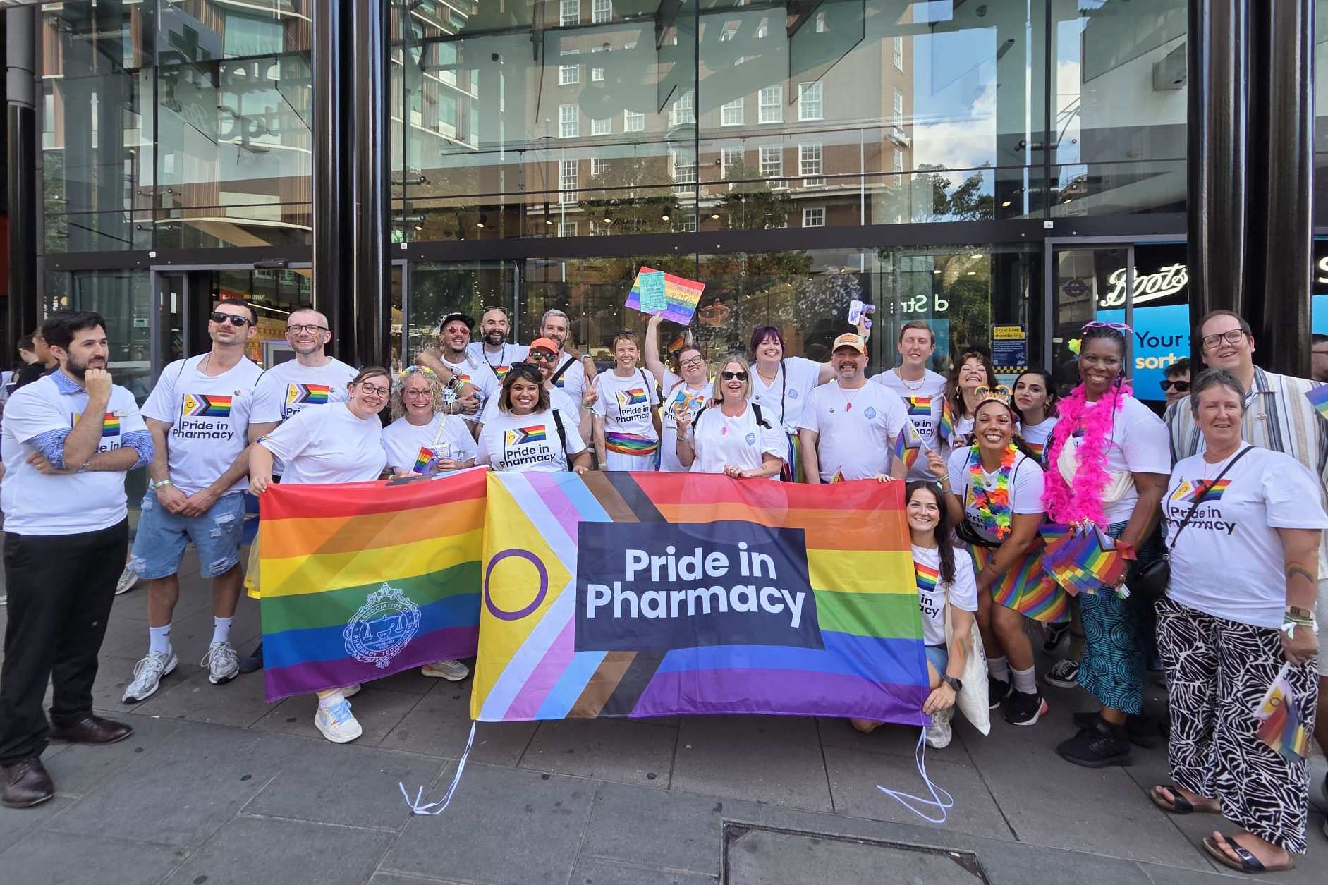 A group of RCPharm workers with pride flags and t shirts stand outside Boots on Oxford Street, London