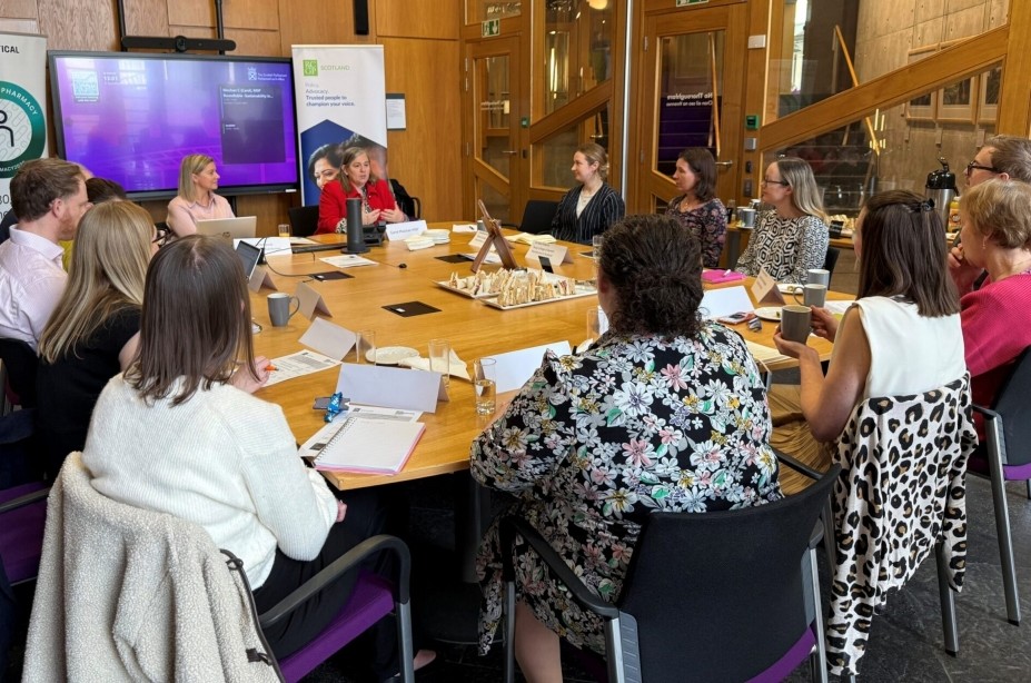 Members of the RCPharm roundtable gathered around a table with a presentation screen discussing sustainability