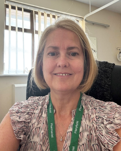 Head and shoulders image of Amanda Powell, member of the ‘Pharmacy: Delivering a Healthier Wales’ delivery board, wearing a pink patterned blouse