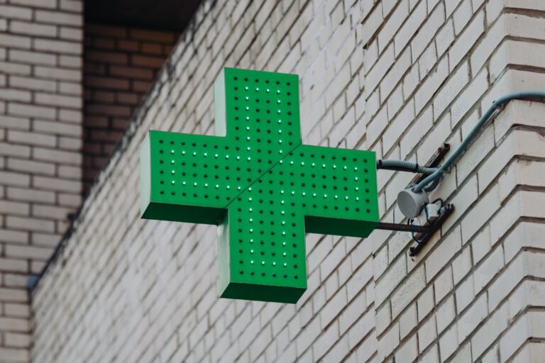 Green cross symbol of pharmacy, attached to wall