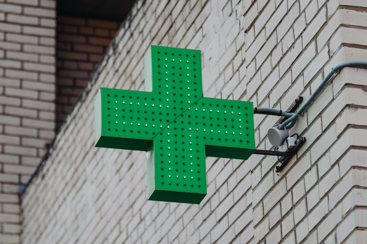 Green cross symbol of pharmacy, attached to wall