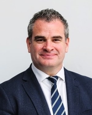 Head and shoulders image of Marc Donovan, member of the ‘Pharmacy: Delivering a Healthier Wales’ delivery board, wearing a black suit