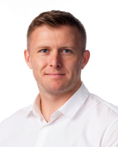 Head and shoulders image of Owain Brooks, member of the ‘Pharmacy: Delivering a Healthier Wales’ delivery board, wearing a white shirt