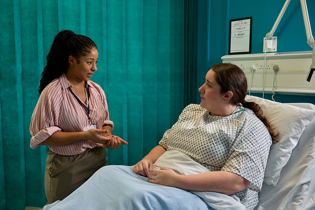Healthcare professional talking to a patient who is in a hospital bed