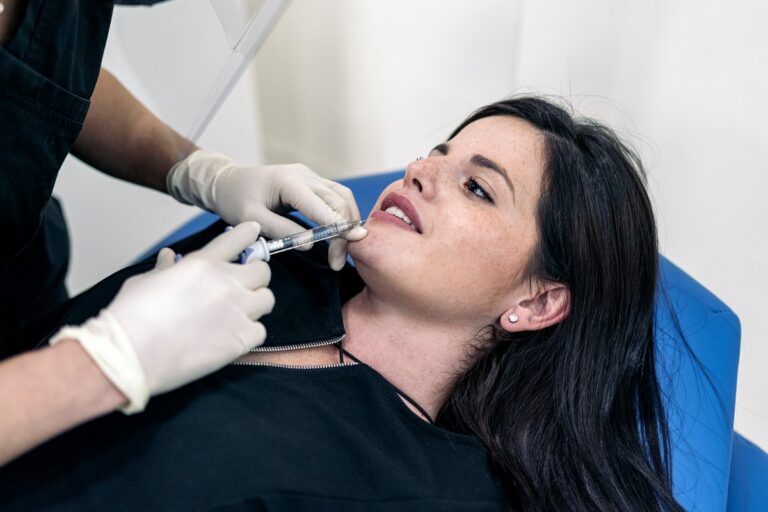 Young woman lying down in stretcher while receiving Botulinum toxin injection in beauty clinic.